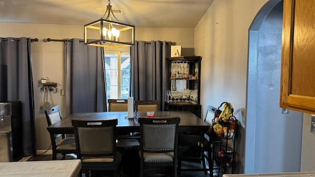 dining area with visible vents, arched walkways, and a chandelier