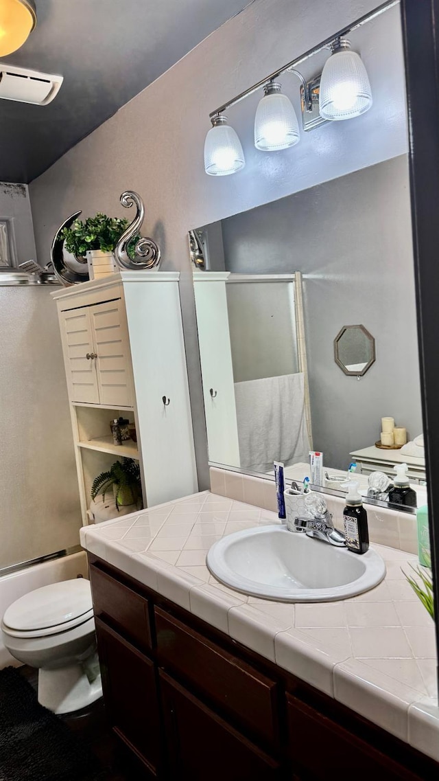 bathroom featuring bath / shower combo with glass door, toilet, and vanity