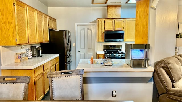 kitchen featuring tile countertops, visible vents, tasteful backsplash, and appliances with stainless steel finishes