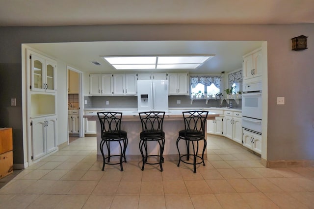 465 Mike Ct, Lemoore, CA 93245 - kitchen featuring white appliances, a warming drawer, light countertops, white cabinets, and a kitchen bar