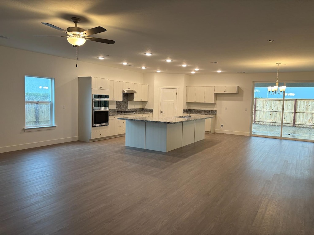 3821 Via Santa Barbara Ave, Madera, CA 93637 - kitchen featuring stainless steel double oven, a chandelier, white cabinets, a center island with sink, and dark wood finished floors