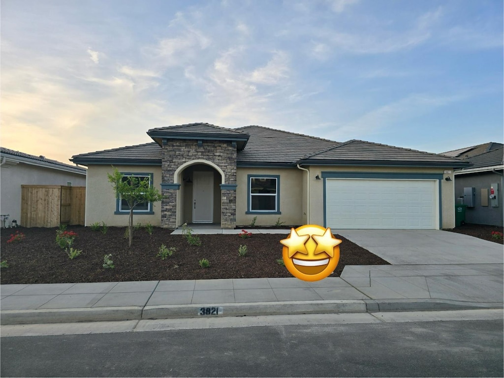 3821 Via Santa Barbara Ave, Madera, CA 93637 - view of front facade with stucco siding, stone siding, a garage, driveway, and a tiled roof
