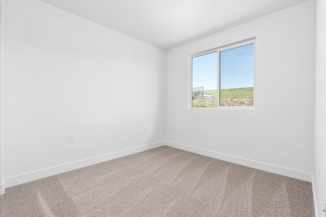 unfurnished room with baseboards and carpet