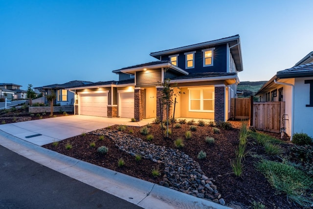 prairie-style house with an attached garage, concrete driveway, and fence
