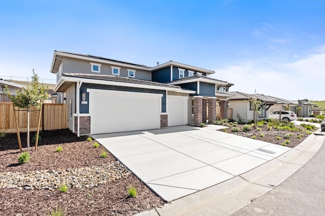 prairie-style home featuring roof mounted solar panels, fence, brick siding, and concrete driveway