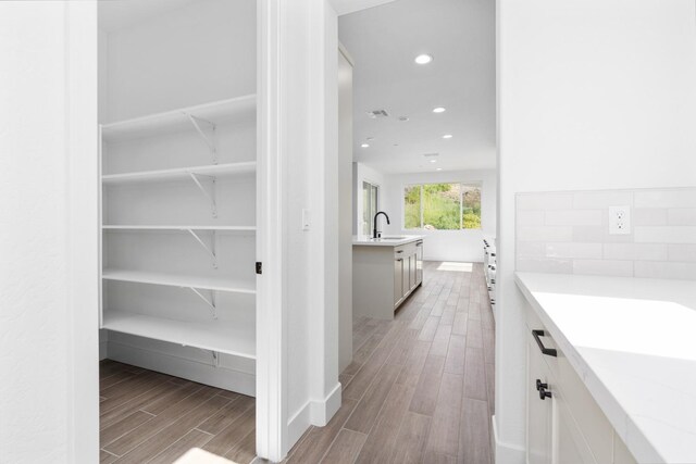interior space with a sink, visible vents, baseboards, recessed lighting, and wood finished floors