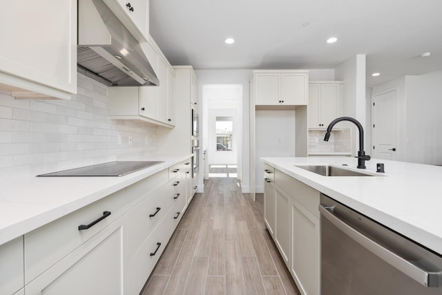kitchen with stainless steel dishwasher, a sink, black electric stovetop, light countertops, and range hood