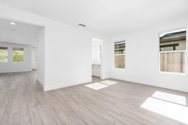 unfurnished room with light wood-type flooring, baseboards, and visible vents