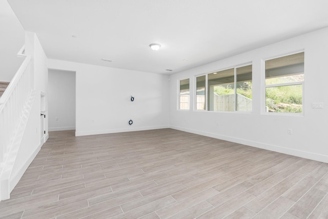 spare room featuring stairway, baseboards, visible vents, and light wood-style flooring