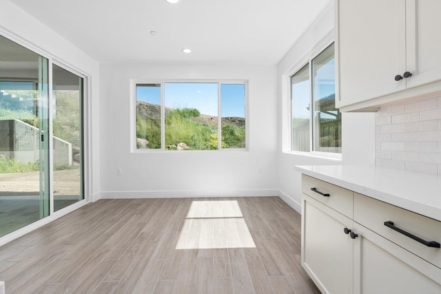 unfurnished dining area with light wood-style flooring, baseboards, and recessed lighting