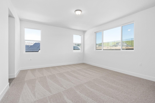 spare room with light carpet and baseboards