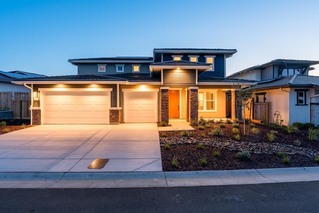 prairie-style home with fence, an attached garage, a tile roof, driveway, and brick siding