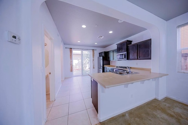 kitchen with visible vents, a kitchen bar, light countertops, stainless steel appliances, and a sink