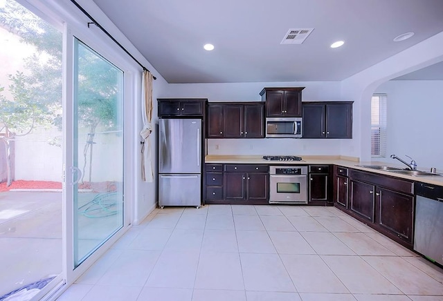 kitchen featuring visible vents, light countertops, appliances with stainless steel finishes, arched walkways, and a sink