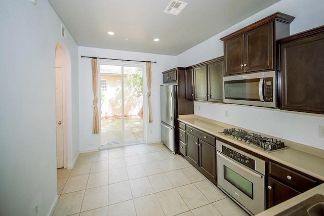 kitchen with visible vents, dark brown cabinets, light countertops, appliances with stainless steel finishes, and arched walkways