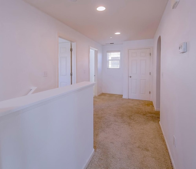 hall featuring recessed lighting, arched walkways, baseboards, and light carpet