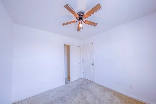 empty room with light colored carpet, baseboards, and ceiling fan