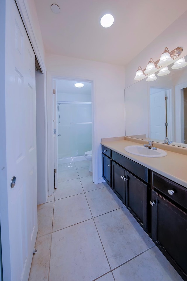 bathroom featuring tile patterned floors, toilet, vanity, and a shower