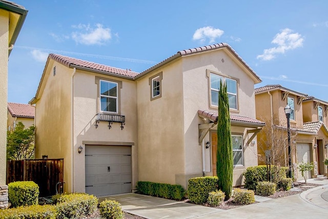 mediterranean / spanish-style house featuring fence, a tiled roof, concrete driveway, stucco siding, and an attached garage