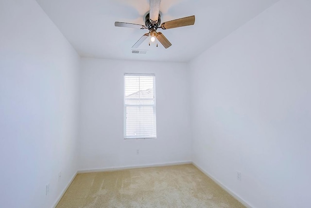 spare room with visible vents, a ceiling fan, light colored carpet, and baseboards