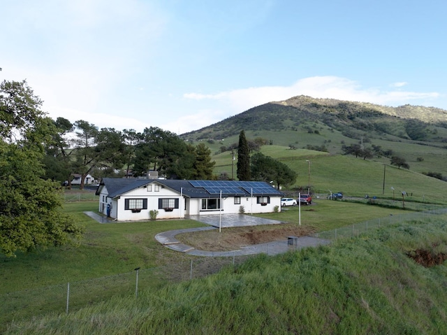 exterior space with a mountain view, a yard, solar panels, and fence private yard