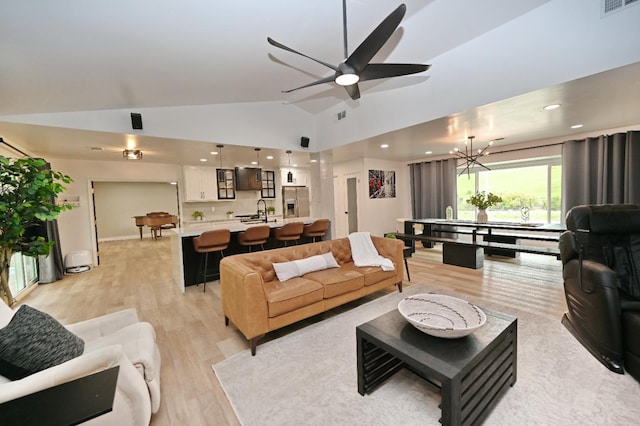 living room featuring light wood finished floors, lofted ceiling, ceiling fan with notable chandelier, and visible vents