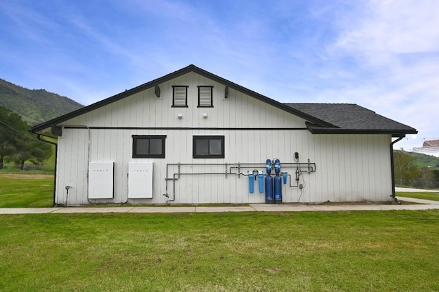 exterior space featuring a yard and roof with shingles
