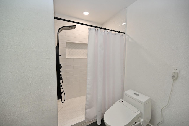 bathroom featuring toilet and tiled shower