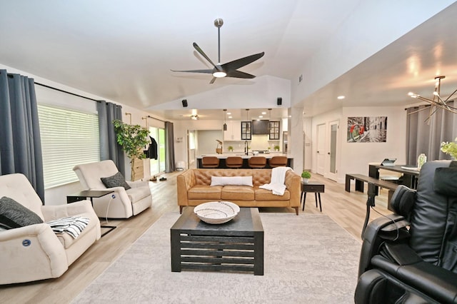 living room featuring light wood finished floors, high vaulted ceiling, and ceiling fan with notable chandelier