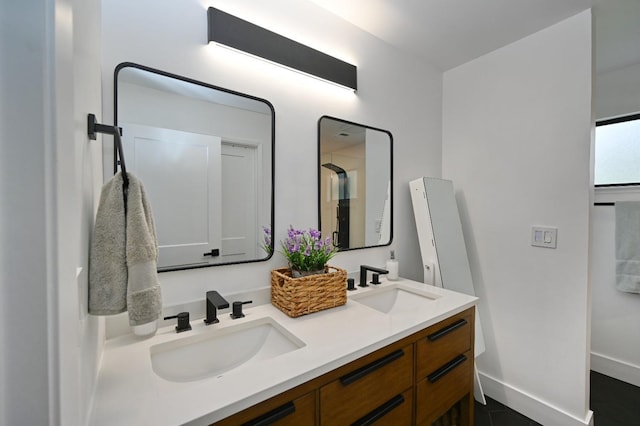 full bathroom with double vanity, baseboards, and a sink