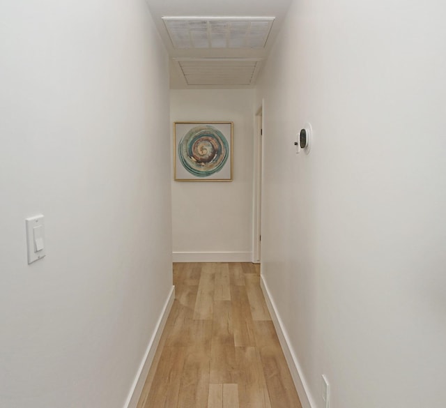 corridor featuring light wood finished floors, visible vents, and baseboards