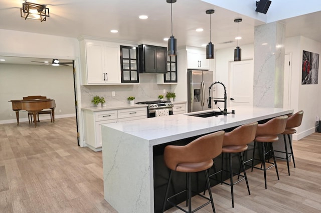 kitchen featuring baseboards, light wood-style floors, stainless steel appliances, and a sink