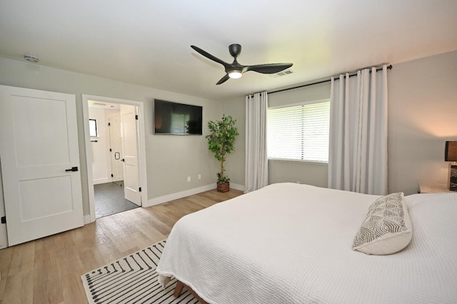 bedroom with wood finished floors, a ceiling fan, visible vents, baseboards, and ensuite bathroom