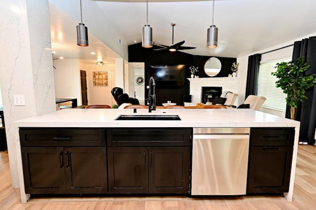 kitchen featuring stainless steel dishwasher, light wood finished floors, ceiling fan, a sink, and open floor plan