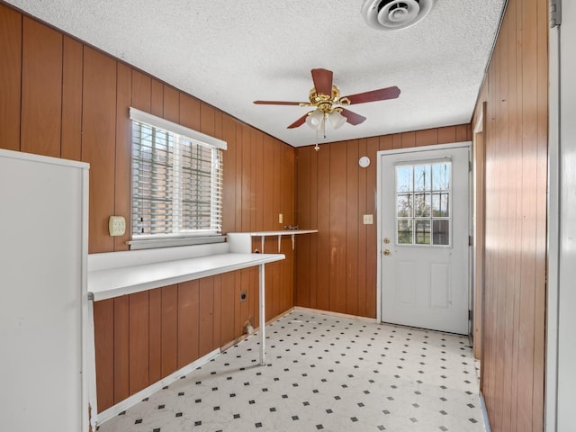 9414 E Belmont Ave, Sanger, CA 93657 - doorway to outside featuring a ceiling fan, wooden walls, light flooring, and a textured ceiling