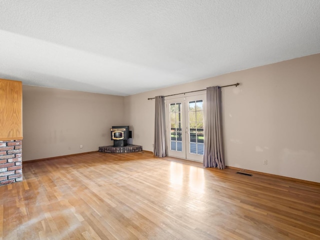9414 E Belmont Ave, Sanger, CA 93657 - unfurnished living room featuring a wood stove, light wood-type flooring, and french doors