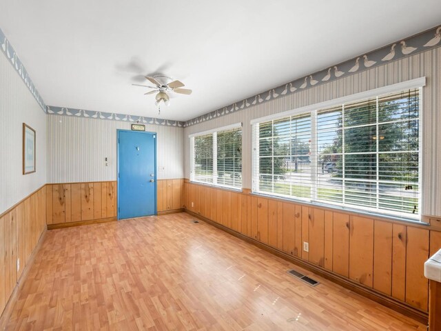9414 E Belmont Ave, Sanger, CA 93657 - spare room with light wood-style flooring, ceiling fan, wainscoting, wood walls, and wallpapered walls