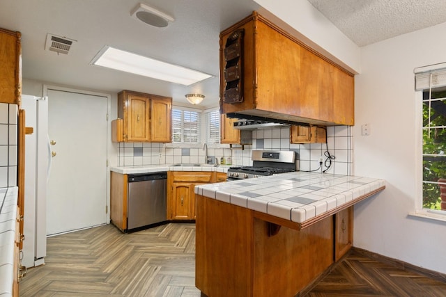 210 S Caesar Ave, Fresno, CA 93727 - kitchen with appliances with stainless steel finishes, a sink, a peninsula, brown cabinets, and a textured ceiling