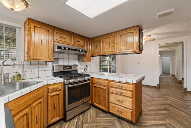 210 S Caesar Ave, Fresno, CA 93727 - kitchen featuring gas range, under cabinet range hood, a sink, a peninsula, and decorative backsplash