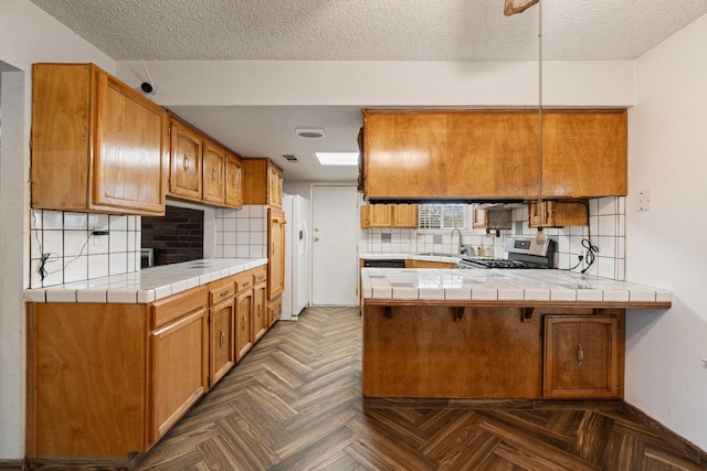 210 S Caesar Ave, Fresno, CA 93727 - kitchen featuring gas stove, a peninsula, a sink, decorative backsplash, and a textured ceiling