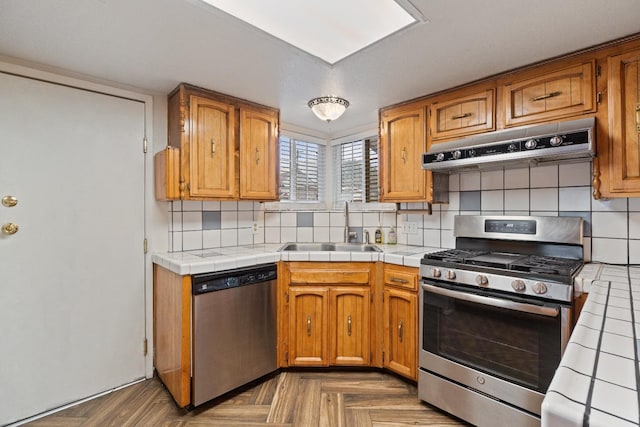 210 S Caesar Ave, Fresno, CA 93727 - kitchen featuring stainless steel appliances, under cabinet range hood, a sink, tasteful backsplash, and tile countertops