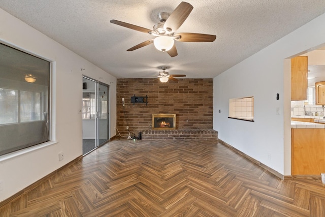 210 S Caesar Ave, Fresno, CA 93727 - unfurnished living room with a ceiling fan, a textured ceiling, baseboards, a sink, and a fireplace