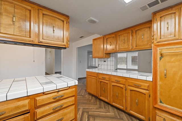 210 S Caesar Ave, Fresno, CA 93727 - kitchen with tile countertops, tasteful backsplash, and brown cabinetry