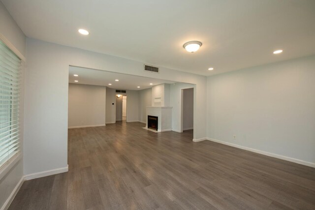 467 E San Bruno Ave, Fresno, CA 93710 - unfurnished living room featuring dark wood-type flooring, baseboards, a large fireplace, and recessed lighting