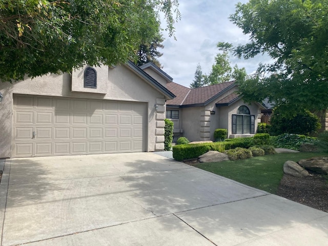 4240 W Sierra Ave, Fresno, CA 93722 - view of front facade with a garage, stucco siding, and driveway