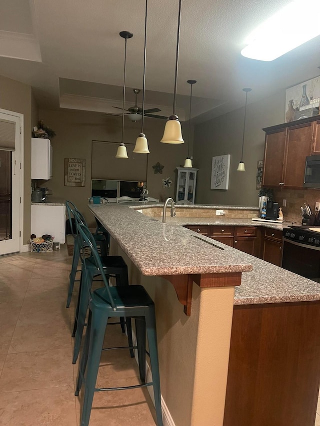 289 S Timberline Dr, Madera, CA 93637 - kitchen with range with gas stovetop, tasteful backsplash, a breakfast bar, light stone countertops, and decorative light fixtures