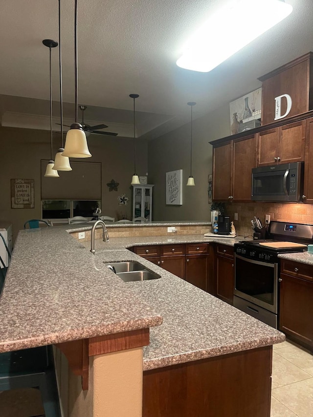 289 S Timberline Dr, Madera, CA 93637 - kitchen featuring black microwave, stainless steel range with gas cooktop, decorative backsplash, light stone counters, and decorative light fixtures