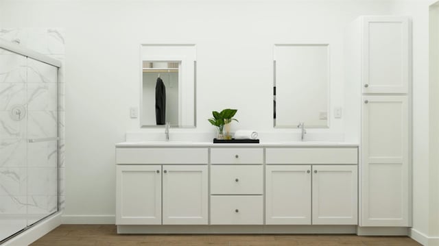 1260 Bloom Ave Unit 34, Clovis, CA 93619 - full bathroom featuring a marble finish shower, double vanity, baseboards, and wood finished floors