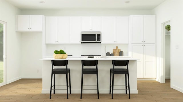1260 Bloom Ave Unit 34, Clovis, CA 93619 - kitchen with light wood-style floors, white cabinetry, a center island with sink, and a kitchen bar