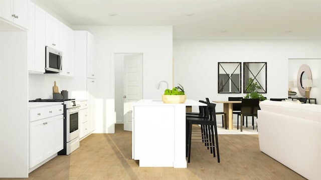 1260 Bloom Ave Unit 34, Clovis, CA 93619 - kitchen featuring stainless steel microwave, white gas range, a kitchen island with sink, and white cabinetry